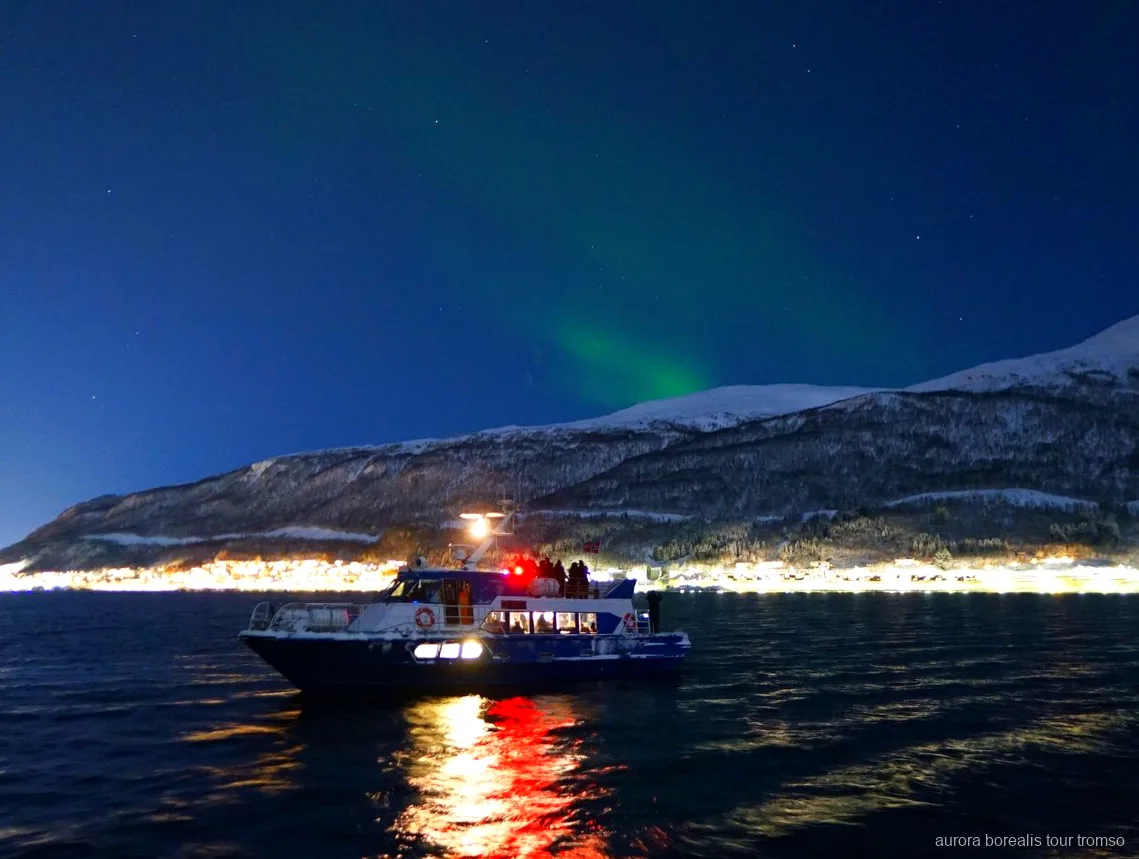 Besætningsmedlem hjælper en gæst med kamerainstillinger på Tromsøs nordlyskrydstogt