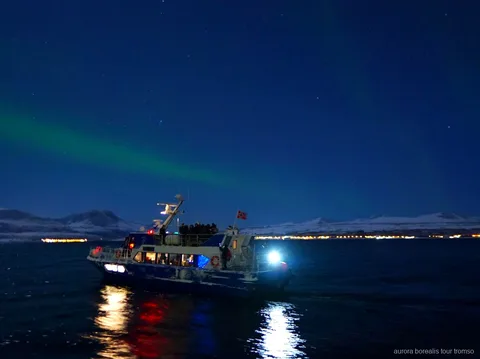 Barco usado no cruzeiro noturno de aurora boreal em Tromso a sair do cais