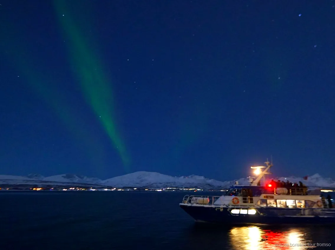 Aurora boreal sobre o fiorde vista do barco do cruzeiro de Tromso