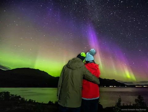 Guide tager et portræt af gæster under Tromsøs nordlysjagt i lille gruppe