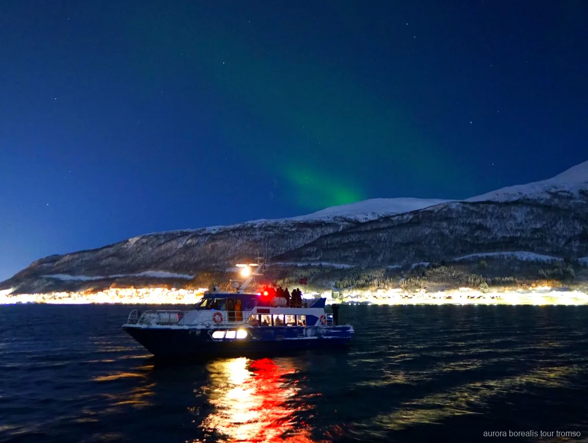 Bemanningslid helpt een gast met camera-instellingen op de Tromso aurora cruise