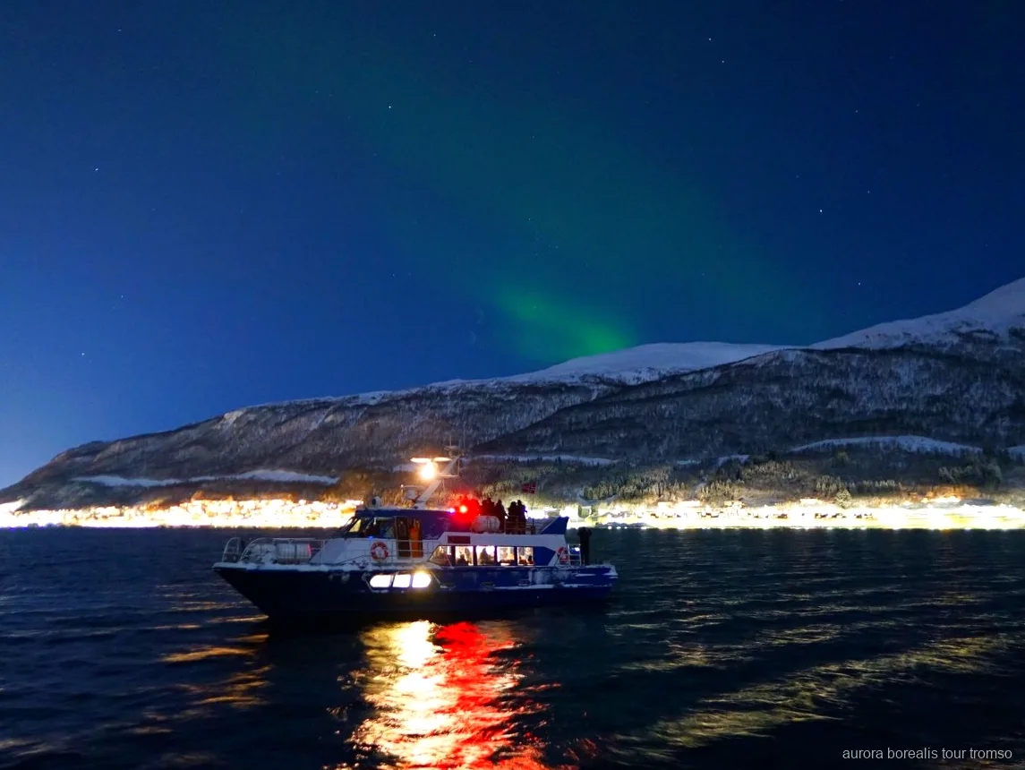Besättningsmedlem hjälper en gäst med kamerainställningar på norrskenkryssningen i Tromsö