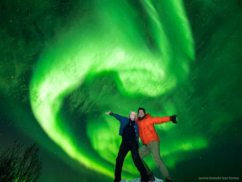 Grupo do tour familiar em carrinha observando a aurora boreal perto de Tromso